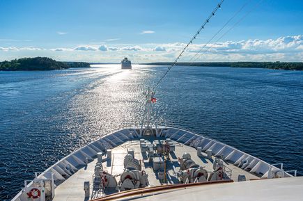 Blick auf den vorderen begehbaren Teil der MS Hamburg mit Sicht auf das Meer und ein weiteres vorausfahrendes Kreuzfahrtschiff