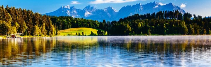 Ein See mit blauem Wasser, umgeben von grünen Bergen.