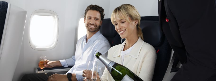 Paar in der Premium class bekommt Getränke im Flugzeug