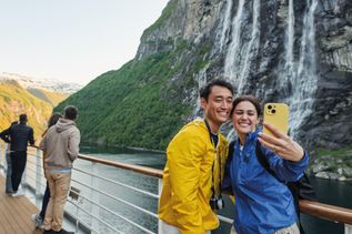 Ein Paar macht in einem norwegischen Fjord ein Selfie auf einem schiff