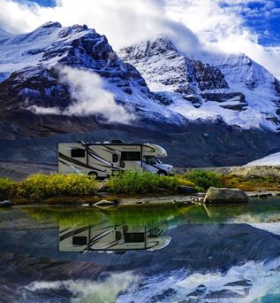 Camper steht am See mit Bergen im Hintergrund