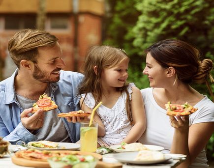 Eine Familie isst an einem Tisch im Freien.