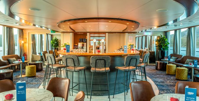 Ein eleganter Salon auf einem Schiff mit vielen Tischen und Stühlen.