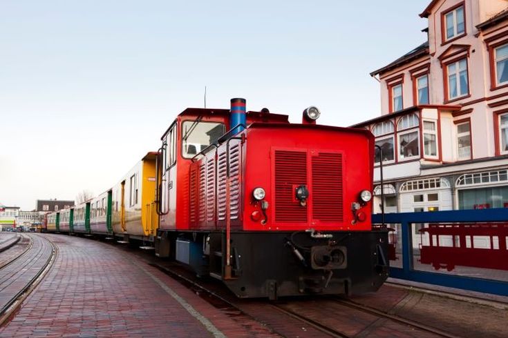 Kleinbahn Borkum. Roter Zug fährt durch die Stadt.