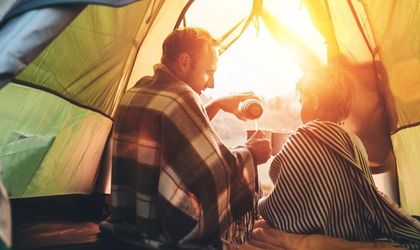 Ein Vater und sein Sohn sitzen gemütlich in einem Zelt, warmes Sonnenlicht fällt herein.
