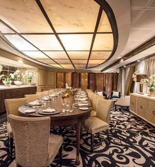 Ein elegantes Restaurant auf einem Schiff mit einem langen Tisch und Stühlen.