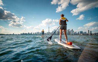 Stand Up Paddle Fahrer auf dem Lake Ontario vor der Skyline von Toronto mit dem CN Tower