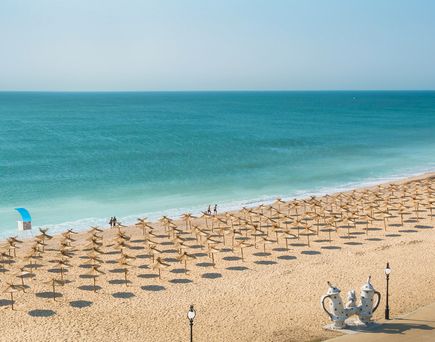 Ein Strand mit Sonnenschirmen und Liegestühlen.