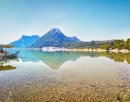 Ein Fischerboot auf einem See oder Fluss, umgeben von Bergen.