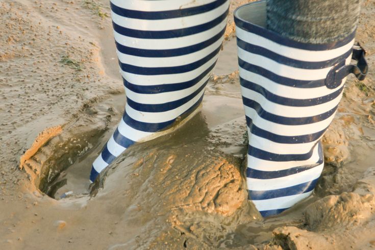 Eine Person trägt gestreifte Hosen und ist teilweise im Sand vergraben.