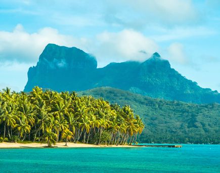 Eine tropische Insel mit einem Berg und Bungalows auf dem Wasser.