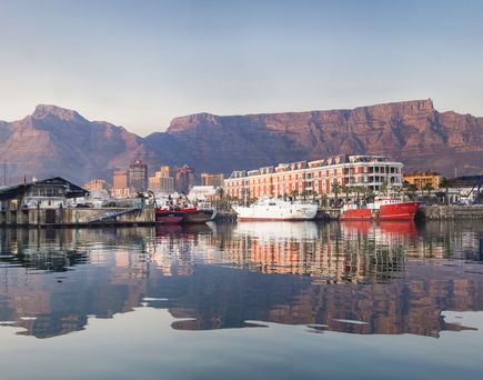 Eine Panoramaansicht der V&A Waterfront in Kapstadt, Südafrika, mit Yachten im Hafen und dem majestätischen Tafelberg im Hintergrund.