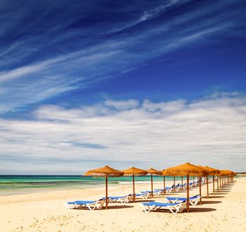 Ein Strand mit Sonnenschirmen und Liegestühlen.