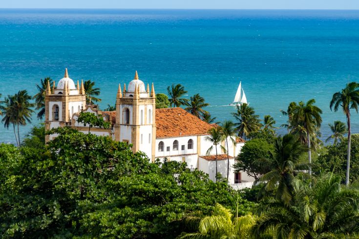 Igreja de CArmo Blick über Palmen auf die Kirche. Im Hintergrund das Meer