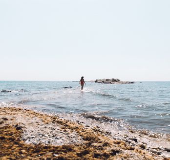 Ein Strand mit flachem Wasser und einer Person in der Ferne.