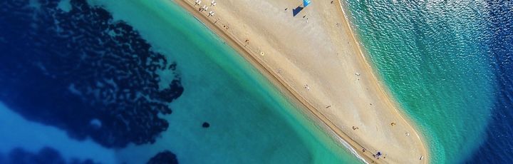Eine Luftaufnahme einer Sandbank, die ins türkisfarbene Meer ragt.