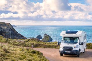 Ein modernes Chausson Titanium Wohnmobil auf Ford Transit Basis steht auf einem grasbewachsenen Feld, bereit für ein Abenteuer in Großbritannien.