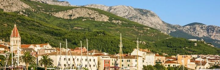 Eine Hafenstadt mit Booten und Gebäuden am Wasser, umgeben von Bergen.