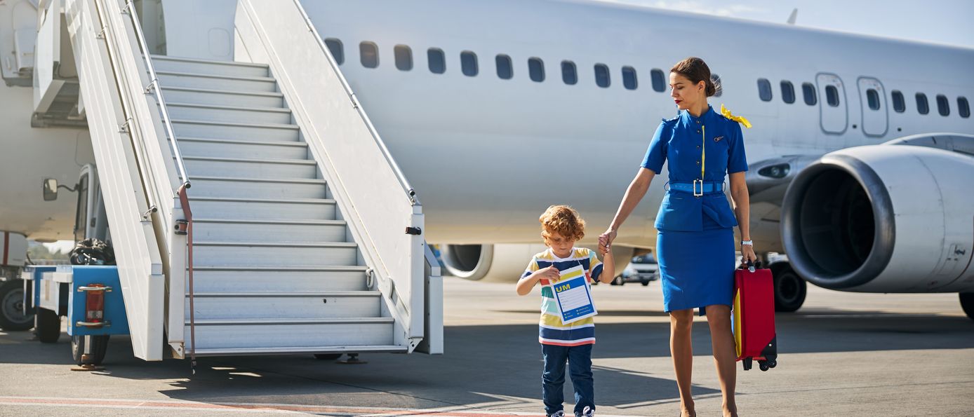 Flugbegleitung mit alleinreisendem Kind vor Flugzeug