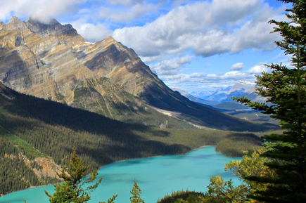 Türkisfarbener Bergsee zwischen bewaldeten Hängen und imposanten felsigen Gipfeln in Westkanada.