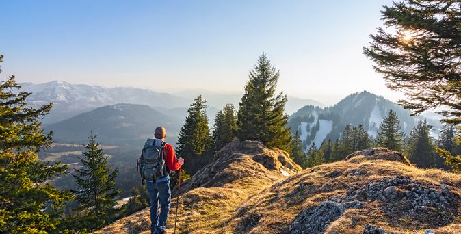 Mann mit Rucksack wandert in den Alpen im Allgäu im Sonnenuntergang