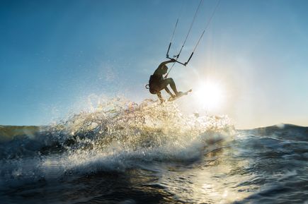 Eine Person fährt auf einem Wakeboard oder Wasserski und springt in die Luft.