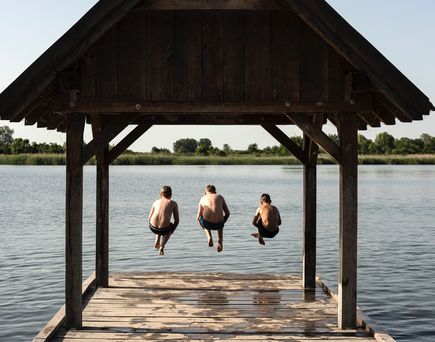 Ein hölzerner Steg führt zu einem Pavillon am See.