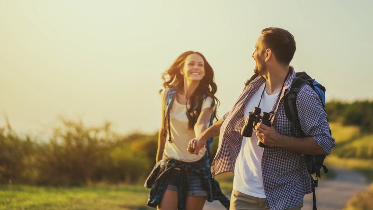 Ein Paar macht eine Wanderung in der Natur, lächelnd und Arm in Arm.