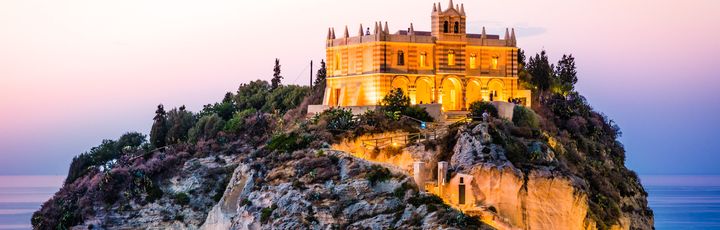 Eine Burg auf einem felsigen Hügel bei Sonnenuntergang.