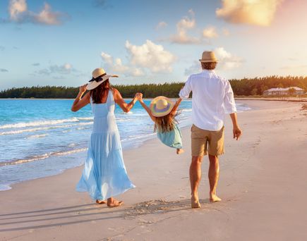 Paar läuft mit KInd am Strand