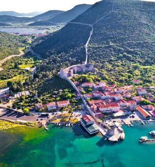 Eine Luftaufnahme einer Küstenstadt mit roten Dächern und Blick auf das Meer.
