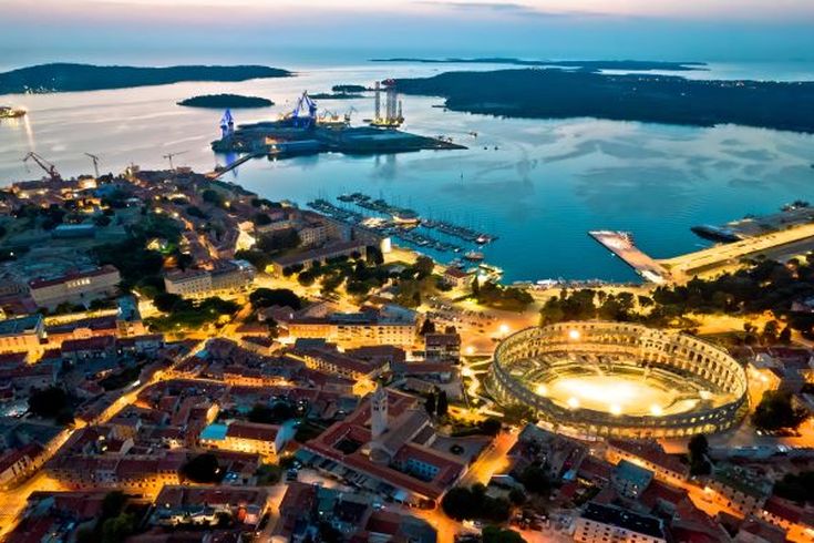 Eine Luftaufnahme von Pula, Kroatien, bei Nacht, mit dem beleuchteten Amphitheater.