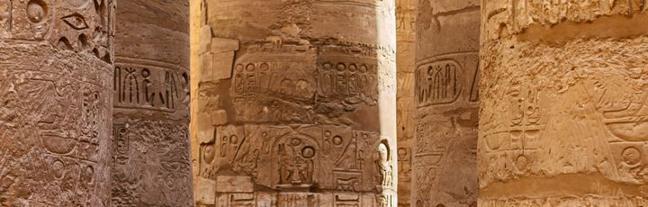 Die Säulenhalle des Karnak-Tempelkomplexes, mit hoch aufragenden, reich verzierten Säulen, die ein blau bemaltes Deckengewölbe tragen.