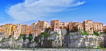 Eine malerische Stadt, die auf steilen Klippen über einem türkisfarbenen Meer thront, mit einem Strand am Fuße der Klippen.