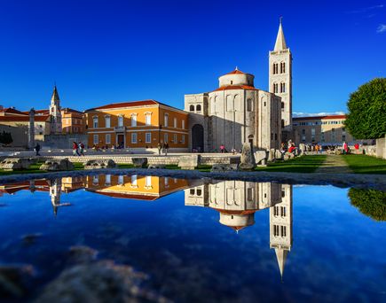 Eine Stadtansicht von Zadar, Kroatien, mit Gebäuden, die sich im Wasser spiegeln.