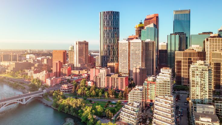 Eine beeindruckende Luftaufnahme der Stadt Calgary, Alberta, Kanada, mit ihrer modernen Skyline, die sich unter einem weiten, blauen Himmel erhebt.