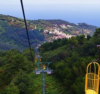 Eine Seilbahn fährt über eine grüne Landschaft.