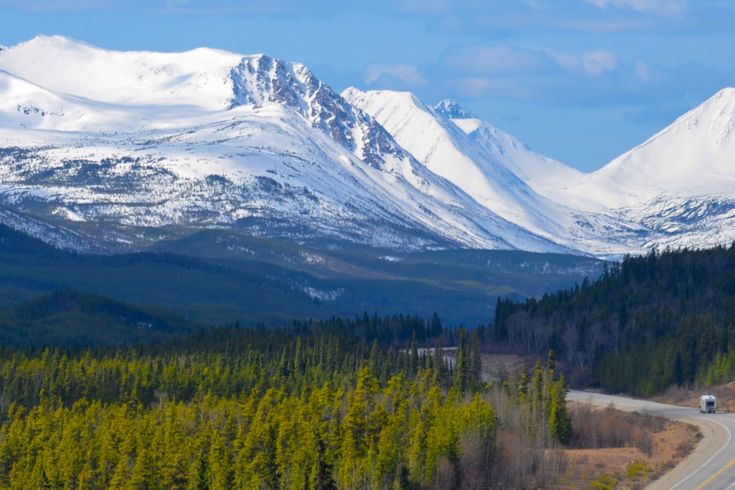 Straße in Richtung schneebedeckte Berge in Kanada