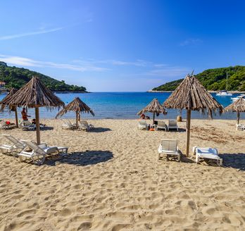 Ein Sandstrand mit Sonnenschirmen und Liegestühlen.