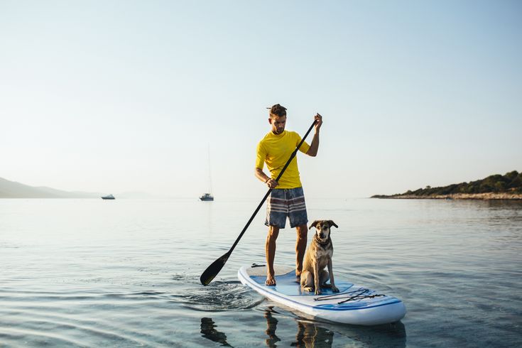 Eine Person steht auf einem Stand-Up-Paddleboard auf dem Wasser.
