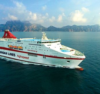 Ein großes, weißes Fährschiff mit roten Streifen und dem Logo "Minoan Lines" auf dem Schornstein fährt auf einem ruhigen blauen Meer.