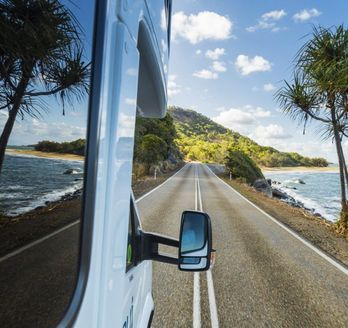 Blick aus einem fahrenden Camper auf eine Küstenstraße