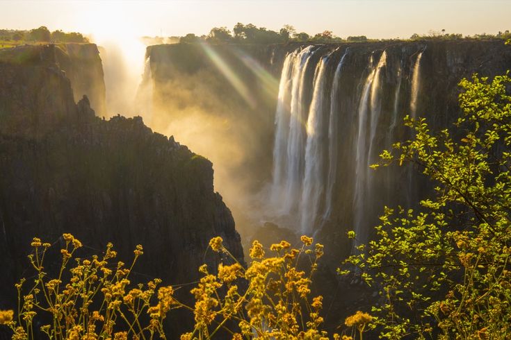  Die mächtigen Victoriafälle in Afrika, die riesige Wassermassen über eine breite Klippe in eine darunterliegende Schlucht stürzen lassen.