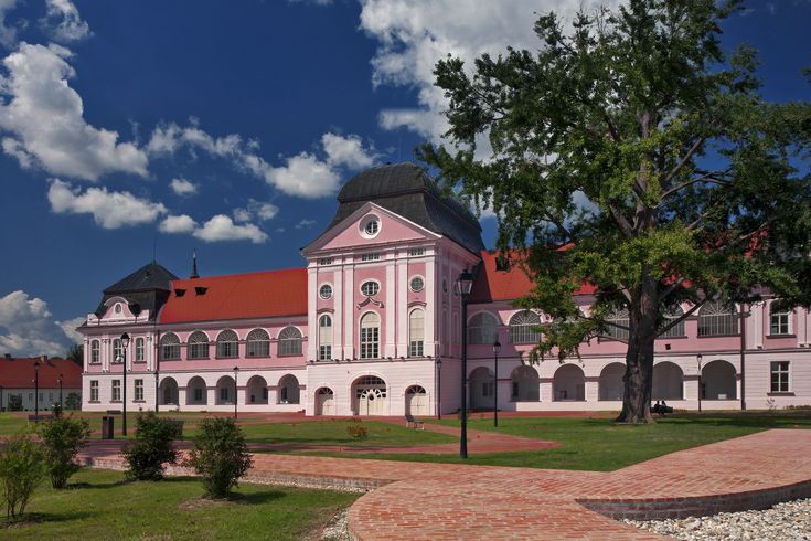 Ein Schloss mit einem roten Dach in einer grünen Landschaft.