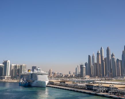 Kreuzfahrtschiff im HAfen von Dubai mit Skyline im Hintergrund