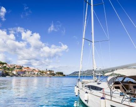 Ein Segelboot im Hafen mit Gebäuden im Hintergrund.