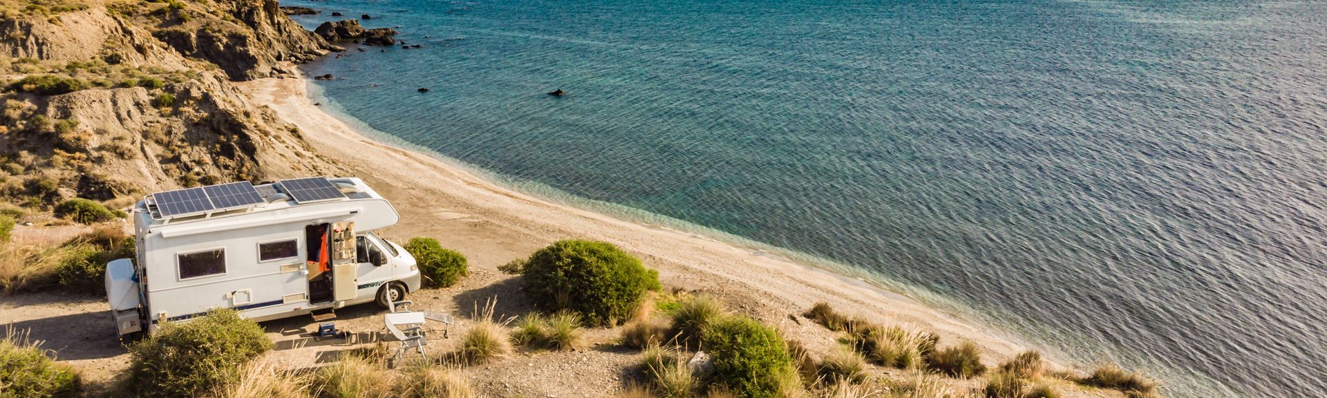  Wohnwagen mit Solarzellen auf dem Dach Camp am Meer, Spanien. Luftaufnahme.