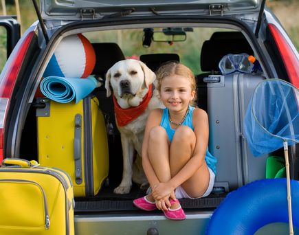 Maedchen und Hund im Kofferraum