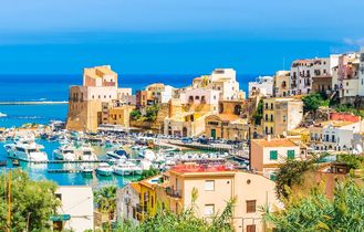 Eine Küstenstadt mit roten Dächern und Blick auf das Meer.