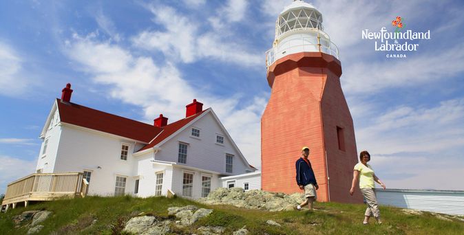 Long Point Leuchtturm in Twillingate. Auf einem Hügel, der Leuchtturm ist unten braun gehalten mit weißer Spitze. Daher ein weißes Gebäude mit rotem Dach.
